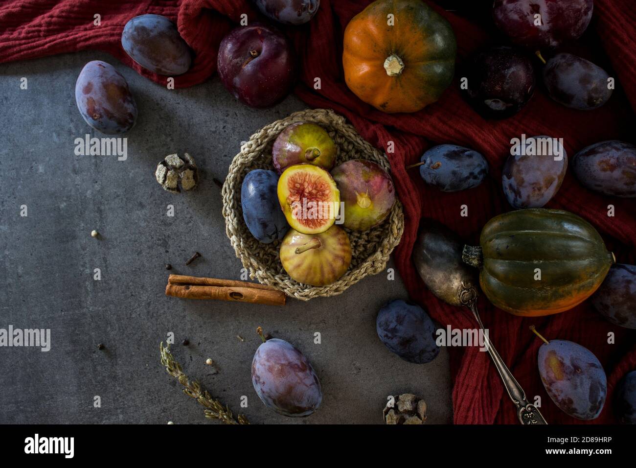 Frisches Obst und Gemüse auf dem Tisch. Foto von oben von Trauben, Kürbissen, Pflaumen und Feigen. Grauer strukturierter Hintergrund. Stillleben im Herbst. Stockfoto