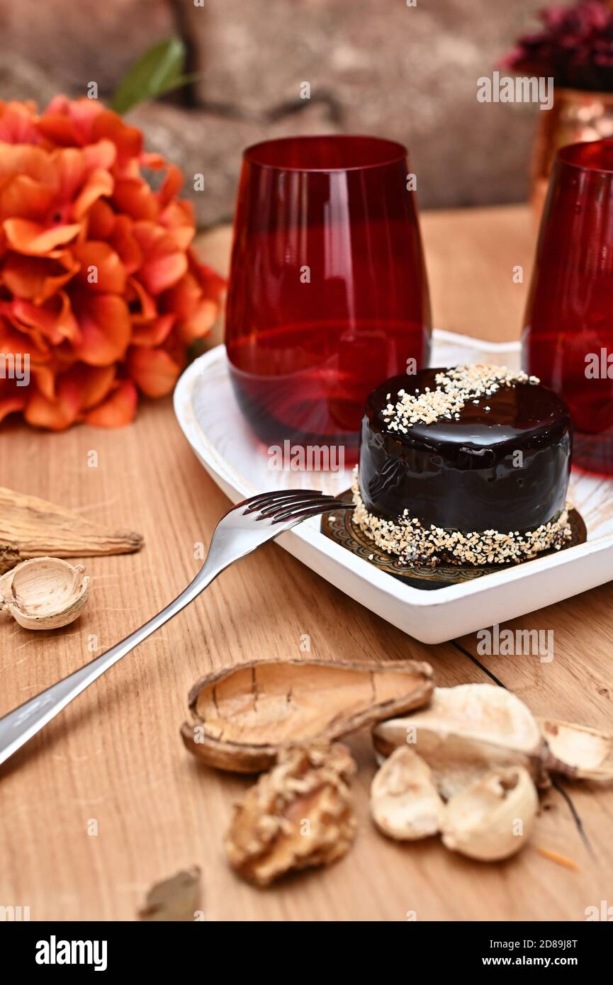 Gourmet Schokoladenkuchen mit Nüssen auf einem herzförmigen Teller Mit rustikalen Dekorationen Stockfoto