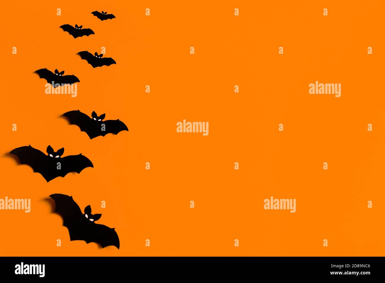 Oranger Hintergrund mit einer Schar von schwarzen Papier Fledermäuse für Halloween, schwarze Papier Fledermaus Silhouetten auf einem orangen Hintergrund, Halloween-Konzept, Copyspace Stockfoto