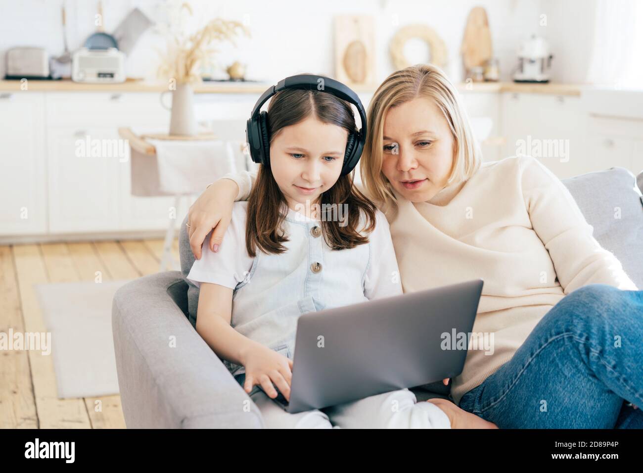 Mutter und Tochter schauen auf den Laptop-Bildschirm und lächeln. Stockfoto