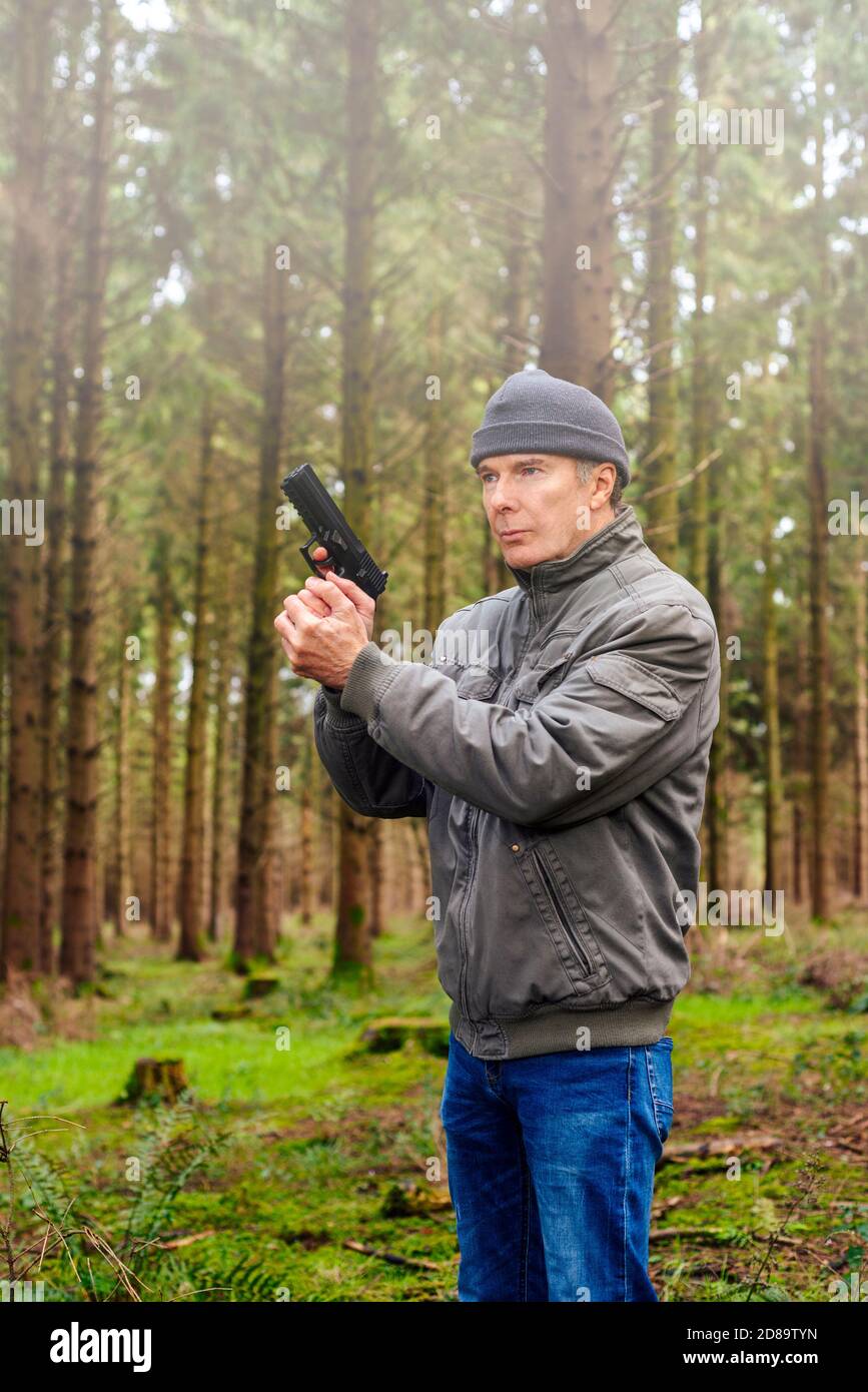 Mann mit Pistole, Waldhintergrund Stockfoto
