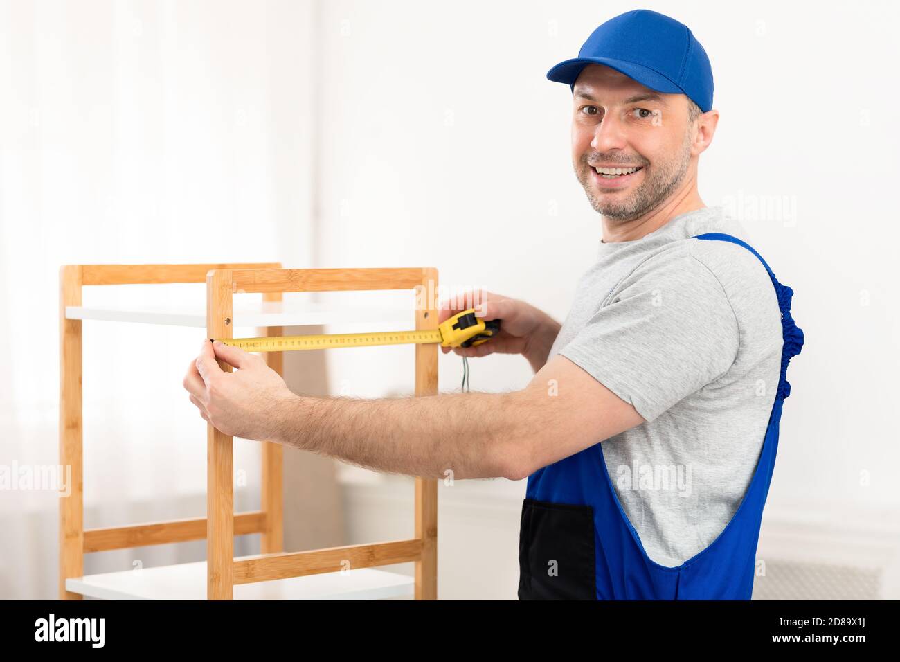 Zimmermann Measuring Shelf Arbeiten Stehen In Innenräumen, Lächelnd Zu Kamera Stockfoto