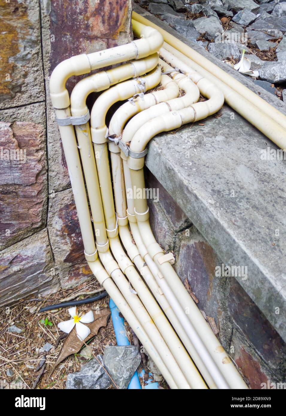 Gelbe elektrische Rohrreihe mit Metallklammer entlang des Fliesenbodens für die Elektroanlage im Restaurant. Stockfoto