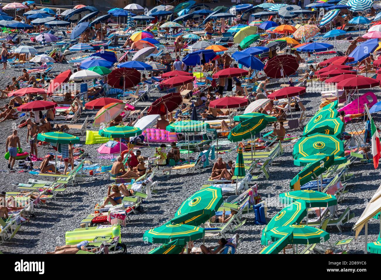 Camogli, Italien. 21. August 2020: Italienischer Strand mit zahlreichen Touristen auf einem Strandurlaub in Italien. Bunte Sonnenschirme und Liegestühle im Sommer. Stockfoto