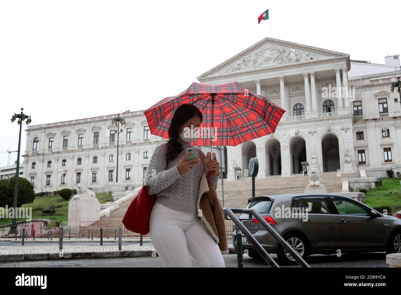 Lissabon, Portugal. Oktober 2020. Eine Frau in einer Gesichtsmaske geht am 28. Oktober 2020 vor dem portugiesischen Parlament in Lissabon, Portugal. Um einer zweiten Welle der COVID-19-Krankheit entgegenzuwirken, müssen Gesichtsmasken ab heute und für mindestens 70 Tage im Freien in ganz Portugal für Menschen ab 10 Jahren getragen werden, wenn eine physische Entfernung nicht gewährleistet werden kann. Portugal verzeichnete in den letzten 24 Stunden 3960 COVID-19 neue Fälle, die höchste Zahl seit Beginn der Pandemie, womit die Gesamtzahl der Infektionen auf 128392 gestiegen ist. Quelle: Pedro Fiuza/ZUMA Wire/Alamy Live News Stockfoto