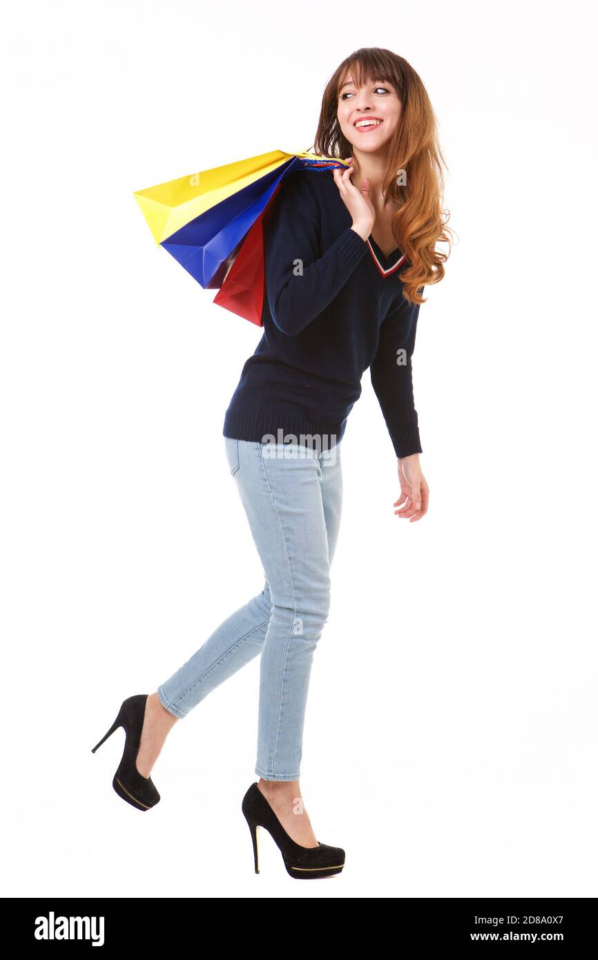 Ganzkörper-Seitenportrait der glücklichen jungen Frau, die weiter geht Isolierter weißer Hintergrund mit Einkaufstaschen Stockfoto