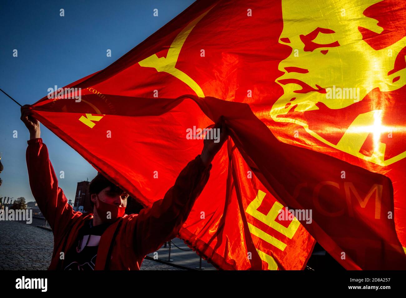 Moskau, Russland. 28. Oktober 2020 EIN Anhänger der kommunistischen Partei hält eine Rote Fahne mit Komsomolabzeichen, während andere sich auf dem Roten Platz versammeln, um den 102. Jahrestag des Komsomol, oder der All-Union Leninistischen Jungen Kommunistischen Liga, der sowjetischen kommunistischen Jugendorganisation, in Moskau, Russland, zu begehen Stockfoto