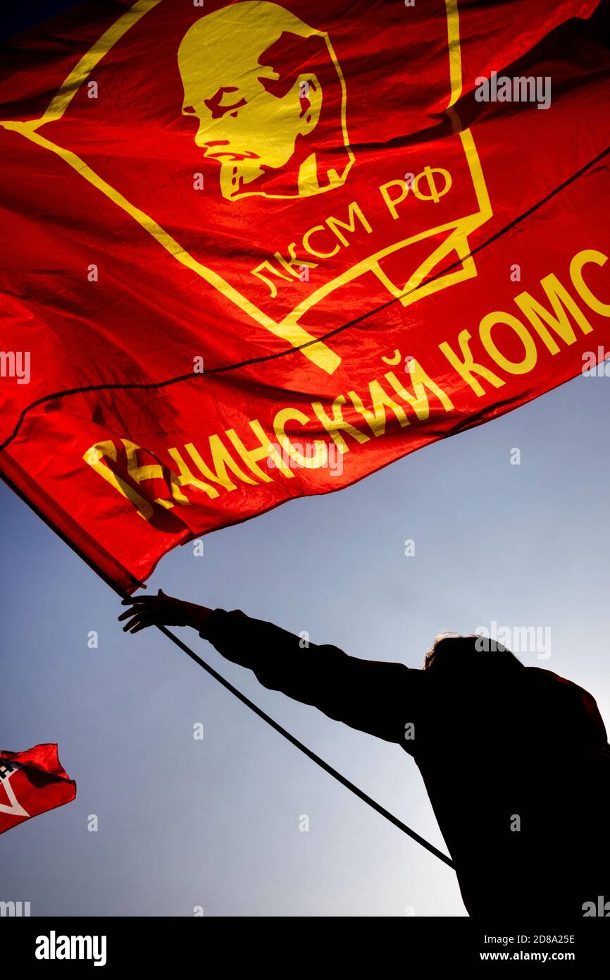 Moskau, Russland. 28. Oktober 2020 EIN Anhänger der kommunistischen Partei hält eine Rote Fahne mit Komsomolabzeichen, während andere sich auf dem Roten Platz versammeln, um den 102. Jahrestag des Komsomol, oder der All-Union Leninistischen Jungen Kommunistischen Liga, der sowjetischen kommunistischen Jugendorganisation, in Moskau, Russland, zu begehen Stockfoto