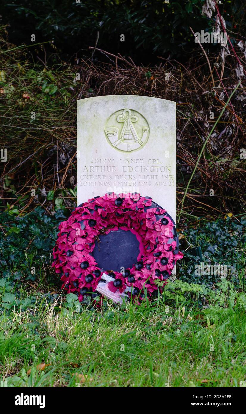 Ein Militärgrab steht allein und an der Seite des Friedhofs in St. Mary's Church, Kirtlington, West Oxfordshire. Mohnkranz. Stockfoto