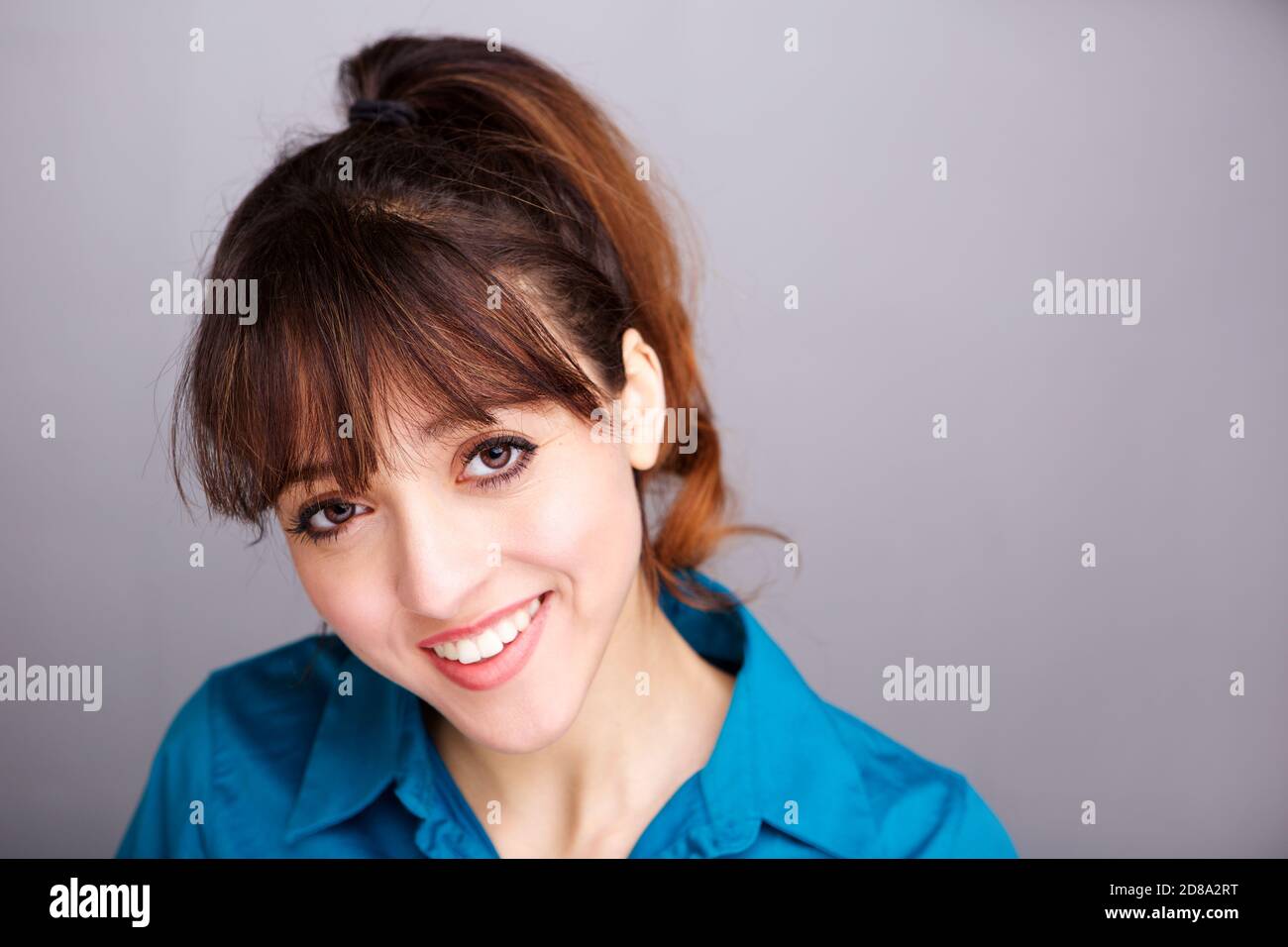 Nahaufnahme Porträt einer lächelnden jungen Frau an der grauen Wand Stockfoto