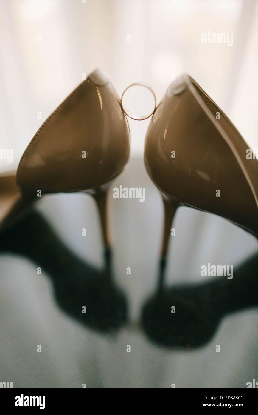 Hochzeitsschuhe und Ringe auf Glastisch Stockfoto