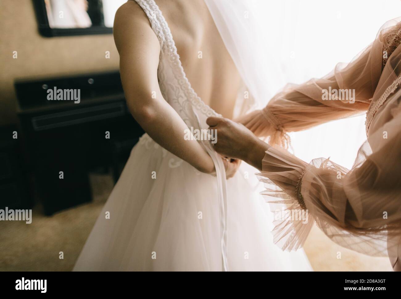 Mama hilft Tochter setzen auf Hochzeitskleid Stockfoto