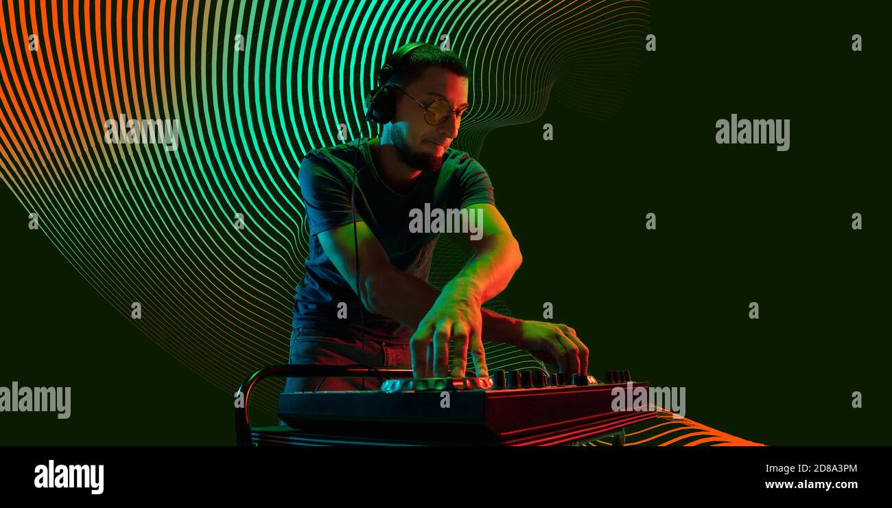 Feuer. Junge kaukasische Musiker in Kopfhörer auf dunklen gepunkteten Hintergrund in Neonlicht mit rot-grünem Licht. Konzept der Musik, Hobby, Festival. Neoned moderne Kunstwerke, Cover, Flyer gestaltet. Stockfoto