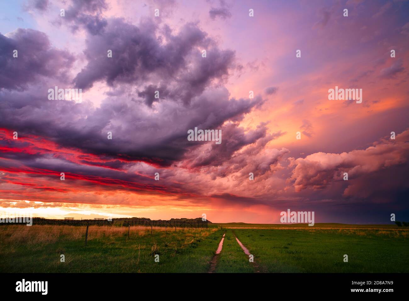 Hinter einem aufziehenden Sturm über der malerischen Landschaft von South Dakota in der Nähe von Camp Crook taucht ein farbenfroher Sonnenuntergang auf. Stockfoto