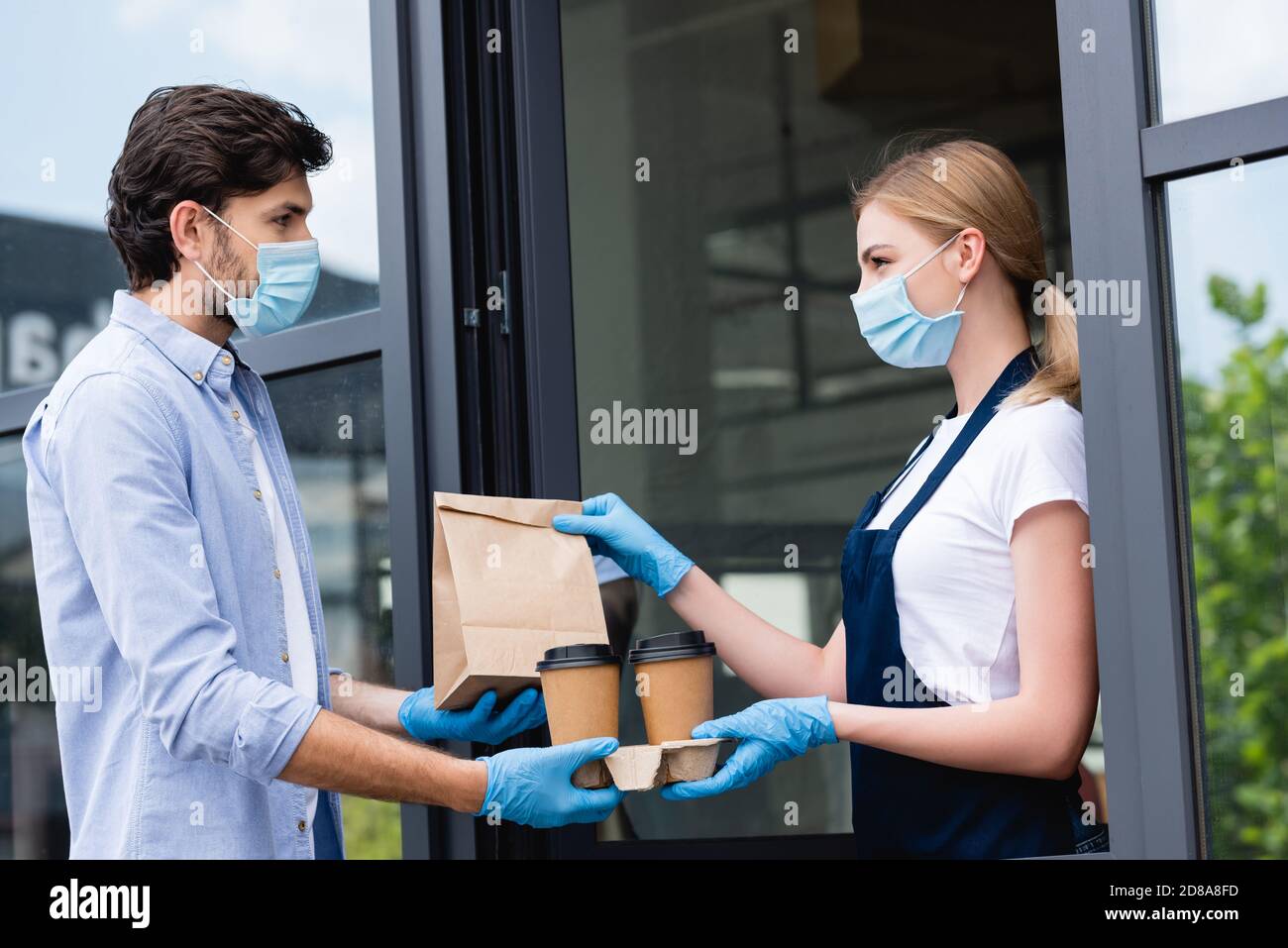 Seitenansicht des Mannes in Latexhandschuhen und medizinischer Maske Bestellung von Kellnerin in der Nähe des Cafés Stockfoto