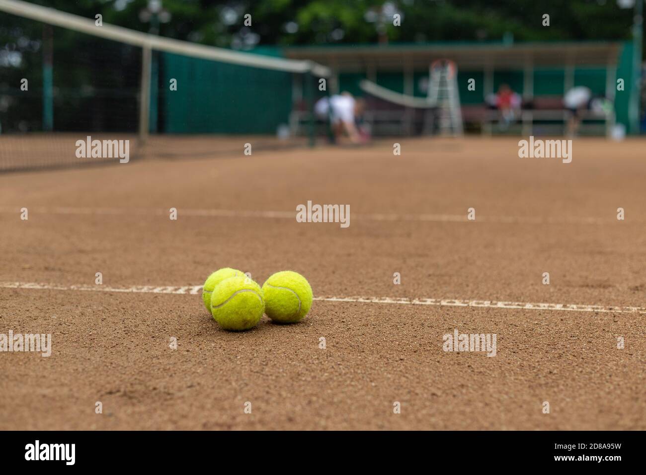 Drei Tennisbälle liegen zusammen auf einem roten Sandplatz. Stockfoto