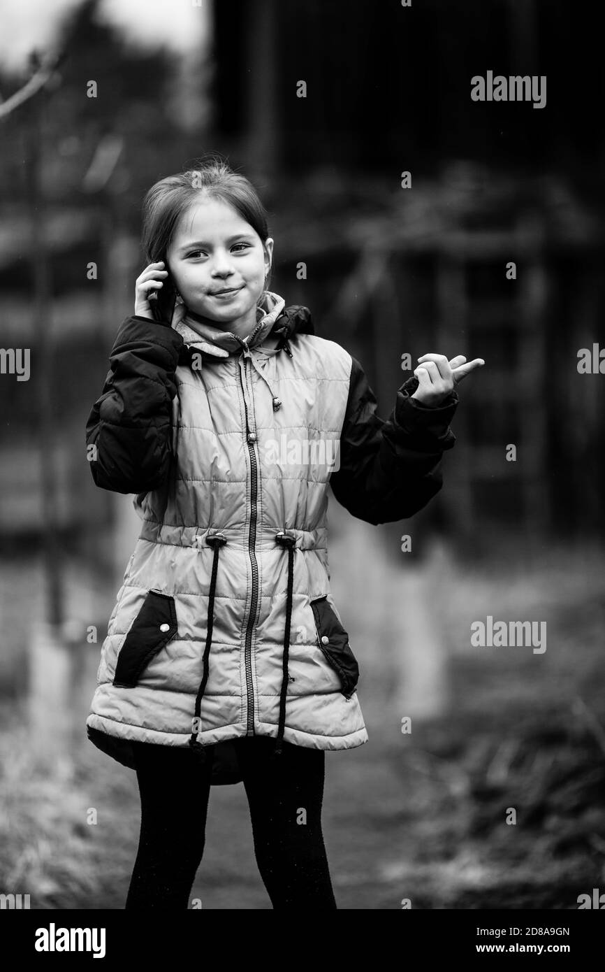 Kleines Mädchen im Gespräch auf mobilen Stand im Freien. Schwarzweiß-Foto. Stockfoto