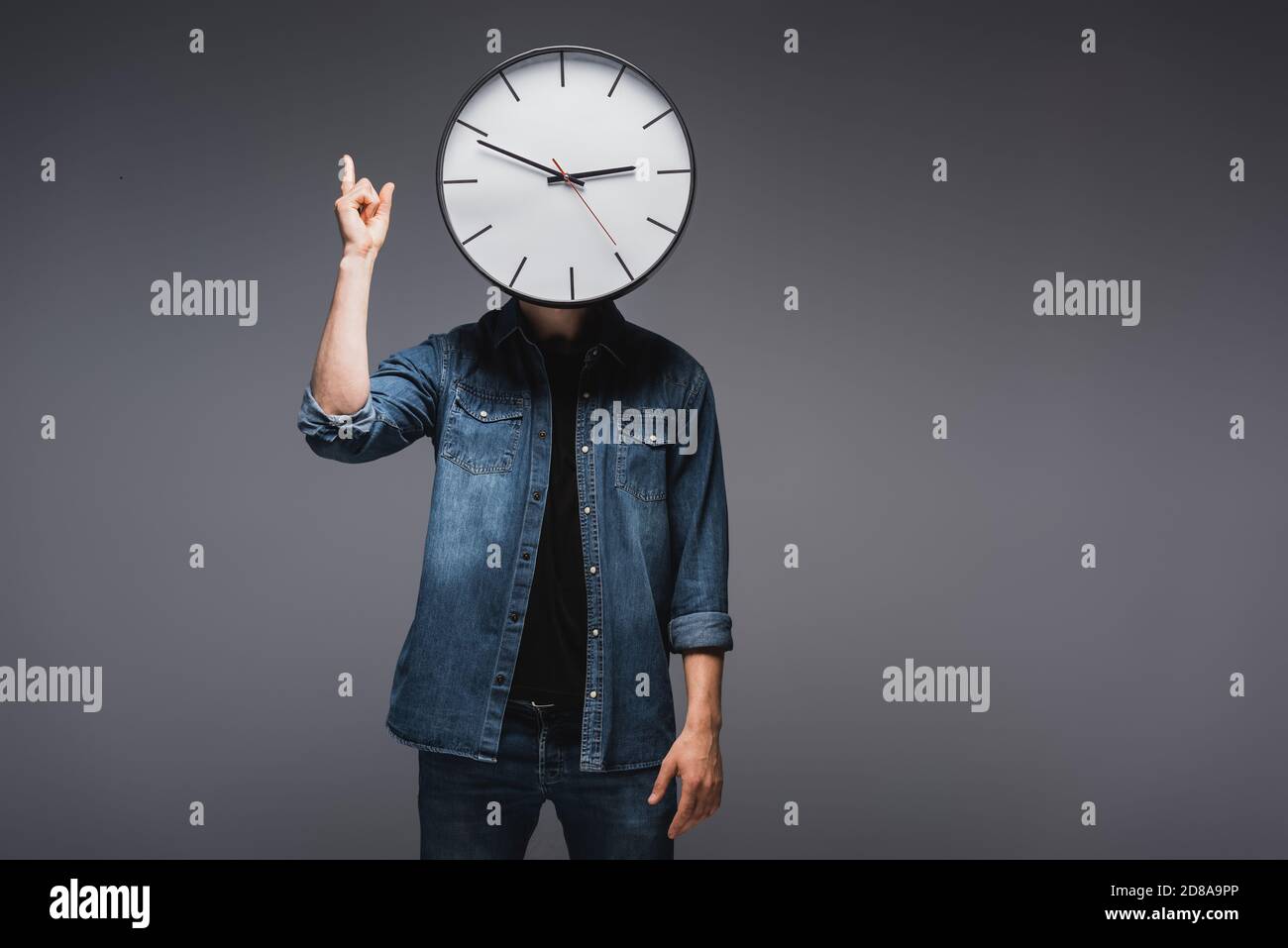 Mann mit Uhr in der Nähe Gesicht zeigt mit Fingern auf grauem Hintergrund, Konzept des Zeitmanagements Stockfoto