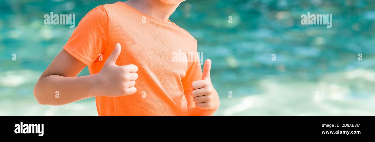 Beschnittene Ansicht des Jungen in orange T-Shirt zeigt Daumen nach oben, Website-Header Stockfoto