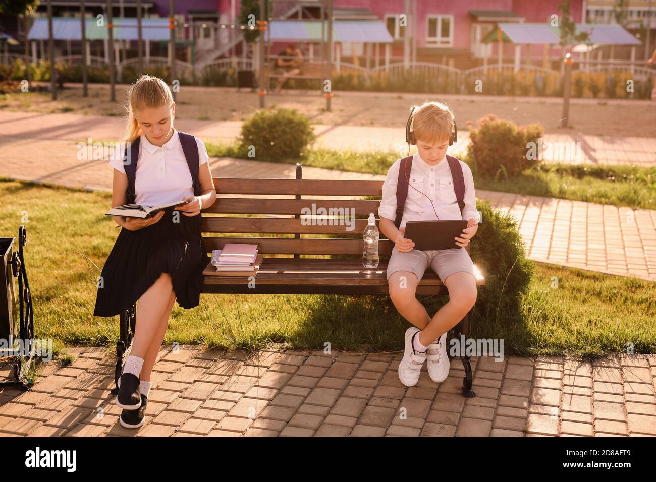 Neue Normalität: Schuljunge und Mädchen in den geschützten Masken kommunizieren und ihre Hausaufgaben auf dem Schulhof machen. Stockfoto