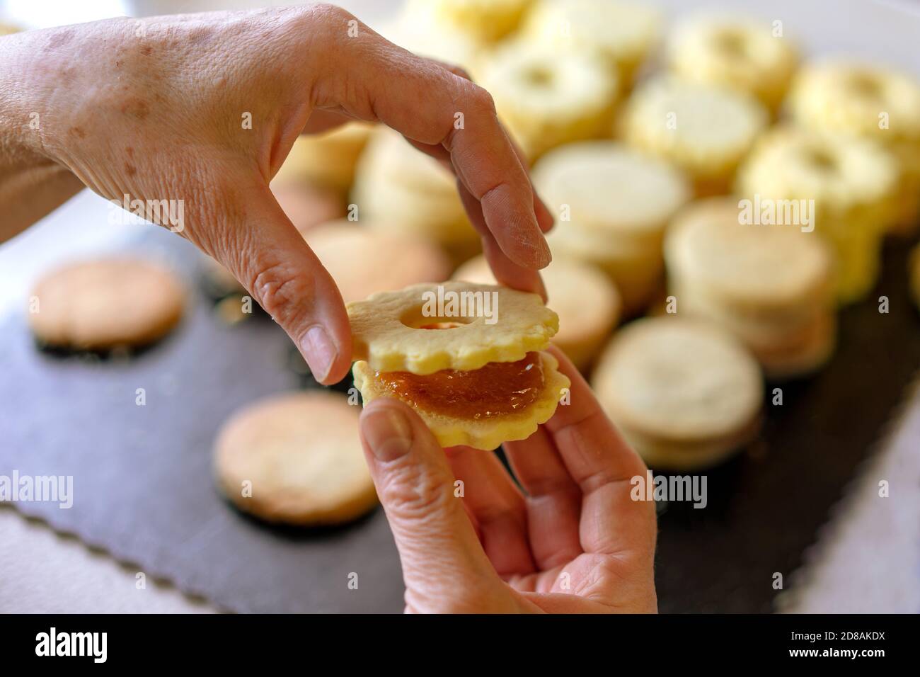 Oma macht traditionelle deutsche spitzbuben weihnachtskekse linzer Keks Cookies gefüllt Mit Marmelade Stockfoto