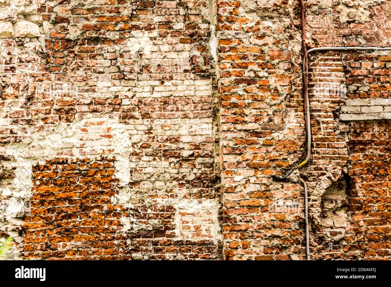 Alte Backsteinmauer mit Spuren der alten Restaurierung und Rekonstruktion des Hauses. Verlassene Haus des siebzehnten Jahrhunderts im Stadtzentrum. Stockfoto