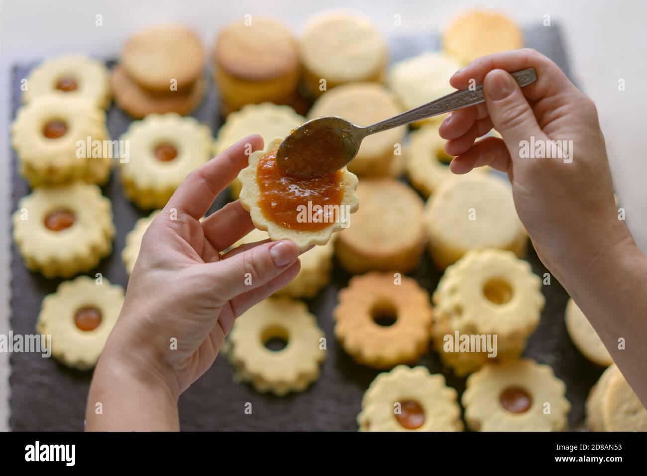 Frau macht traditionelle deutsche spitzbuben weihnachtskekse linzer Keks Cookies gefüllt Mit Marmelade Stockfoto
