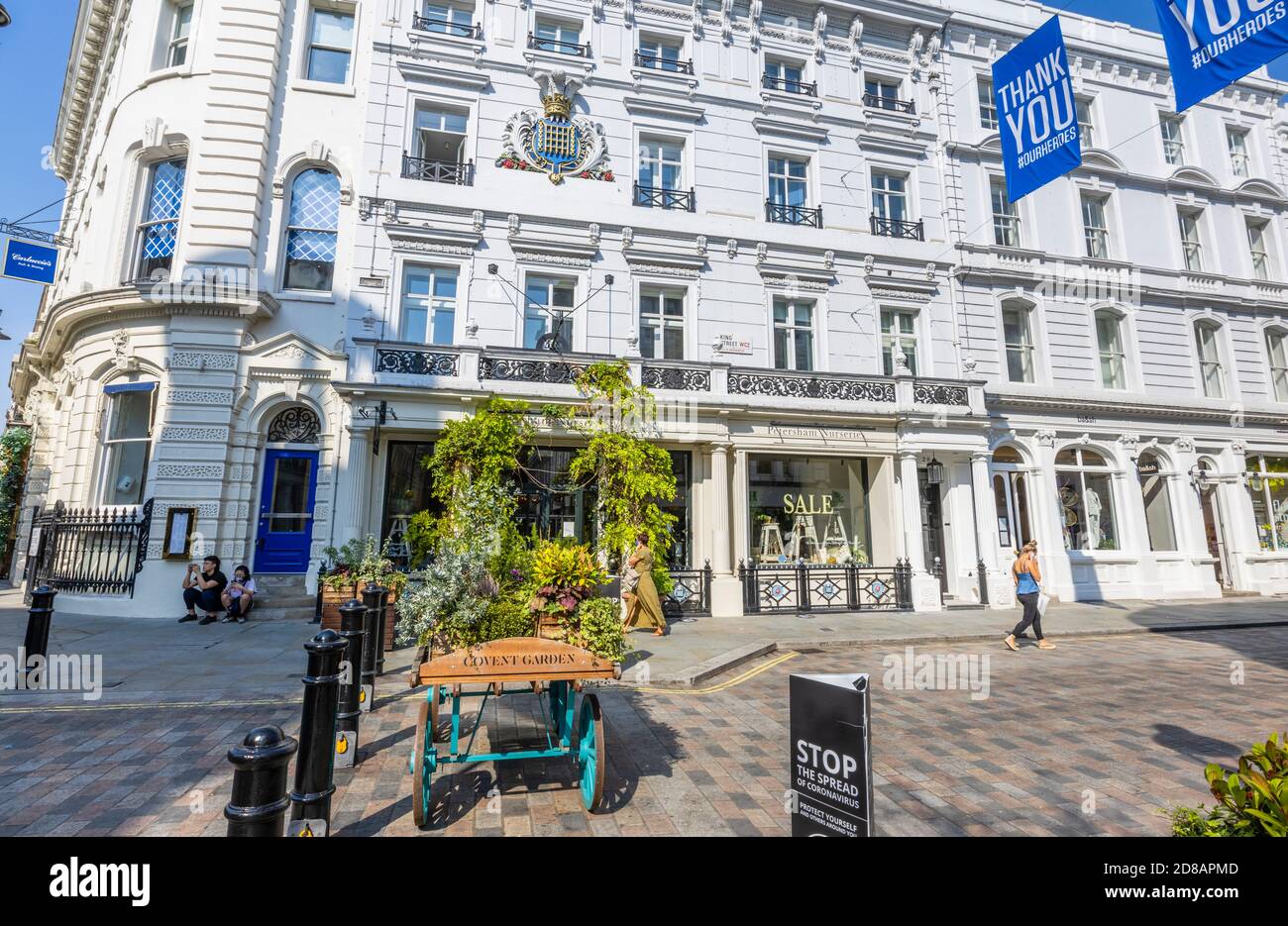 Dekorative Barrow in King Street mit dem Namen Covent Garden, London WC2 an einem sonnigen Tag außerhalb Petersham Nurseries Shop und Café eingeschrieben Stockfoto