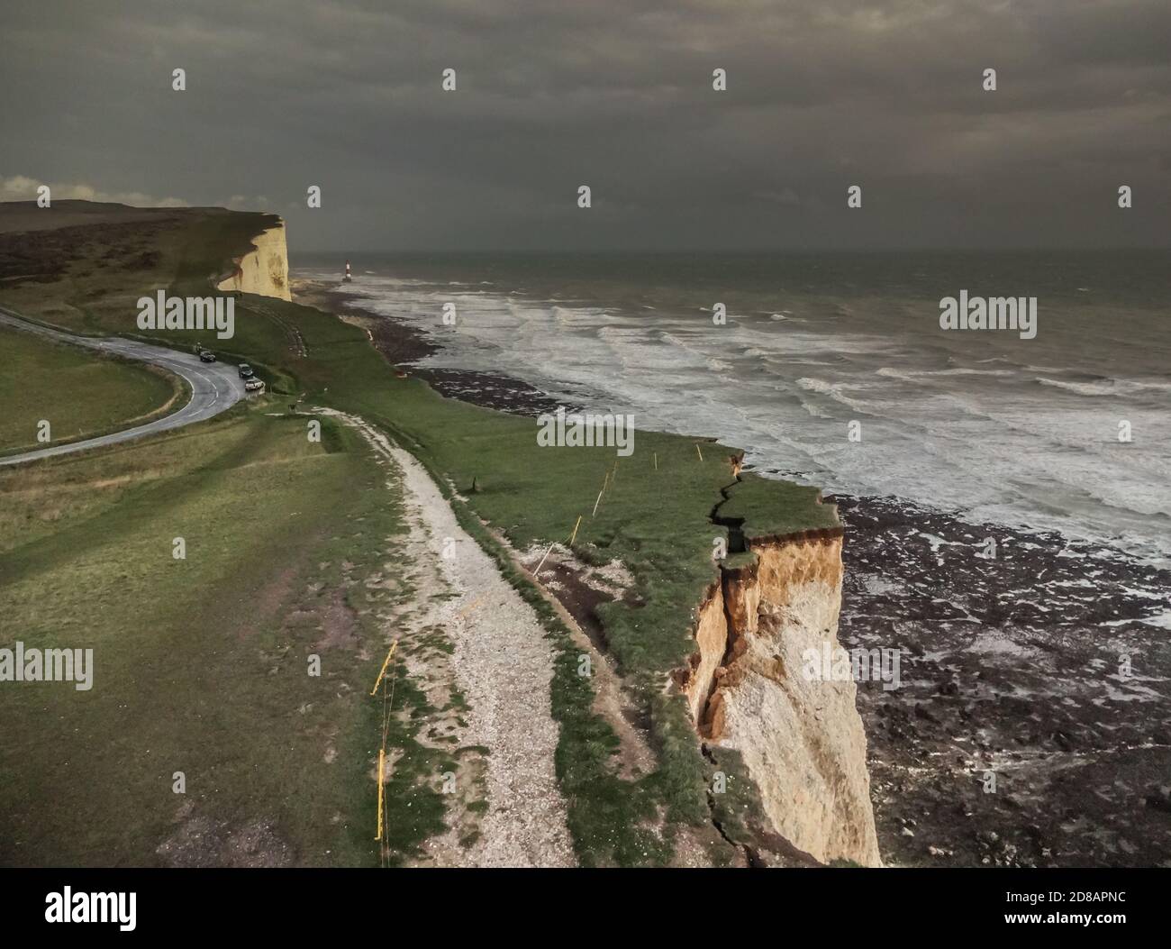 Eastbourne, East Sussex, Großbritannien. Oktober 2020. Dunkler Himmel und sintflutartiger Regen über den Kreidefelsen. Beachy Head Leuchtturm in der Ferne. Während die Erosion zunimmt, während die Kreide weich wird, hängt dieser große Brocken immer noch an. Die Öffentlichkeit wird erneut vor der extremen Fragilität der Klippen mit erhöhtem plötzlichem Gesteinsfallrisiko gewarnt. Der Fotograf verwendete die entsprechende Ausrüstung und war nicht am Rand. Kredit: David Burr/Alamy Live Nachrichten Stockfoto