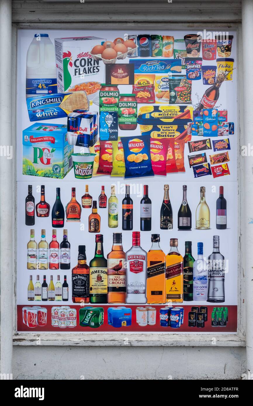 Werbeplakat für beliebte Marken von Lebensmitteln und alkoholischen Getränken im Fenster eines Lebensmittelladen, Großbritannien Stockfoto