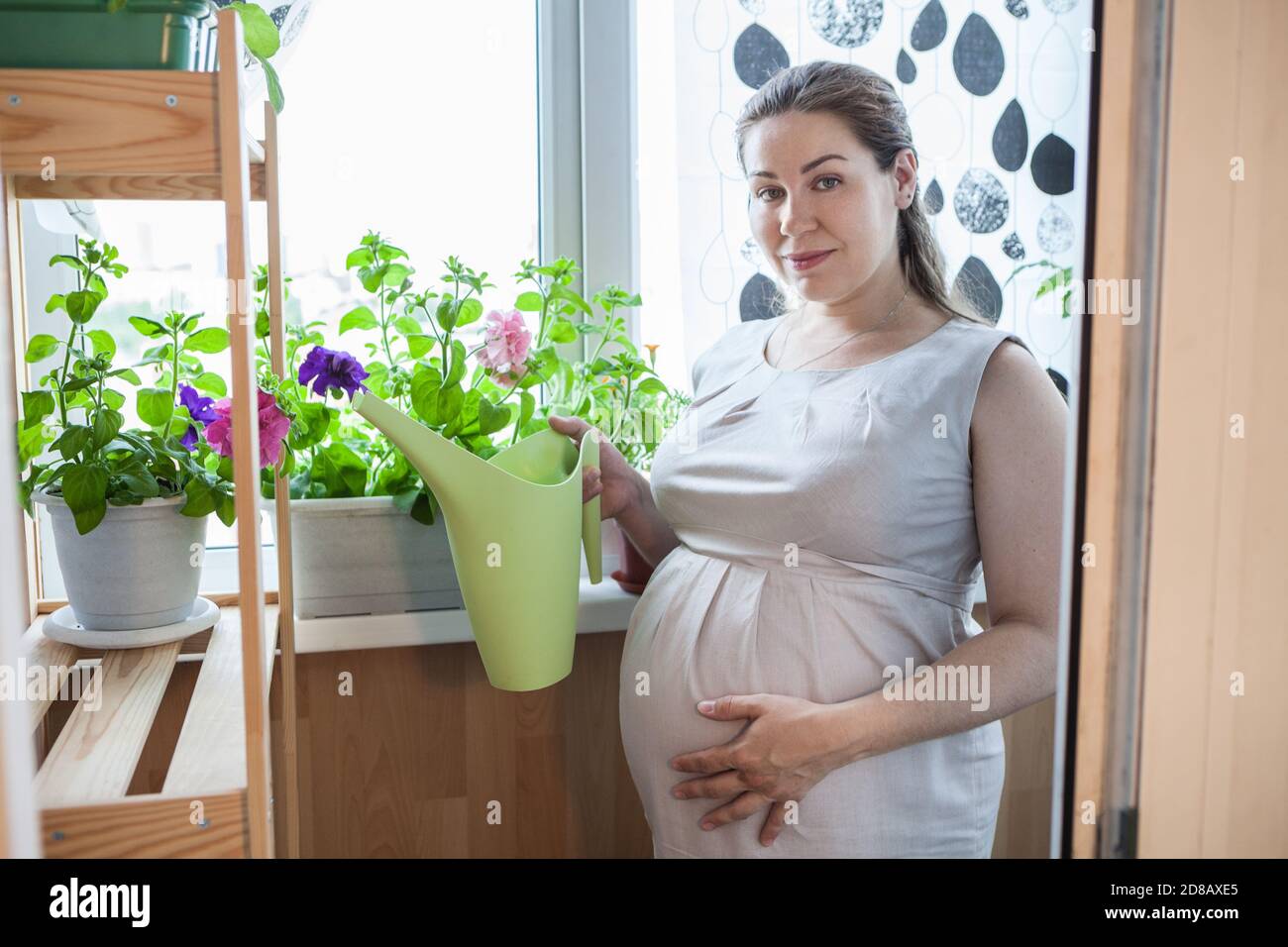 Frau Hausgärterin kümmert sich um ihre Blumen, stehen mit Gießkanne in der Hand Stockfoto