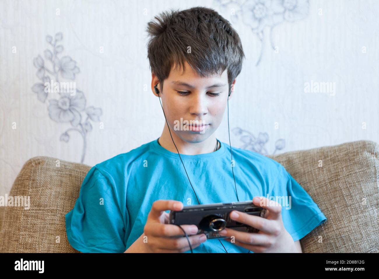 Porträt eines kaukasischen Teenagers mit großem Smartphone oder Spielkonsole in den Händen, Spielen oder Engagement über soziale Medien Stockfoto