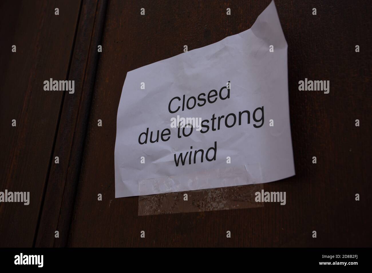 Ein schmuddeliges Papierschild an der Tür mit der Aufschrift "geschlossen wegen" Starker Wind“ Stockfoto