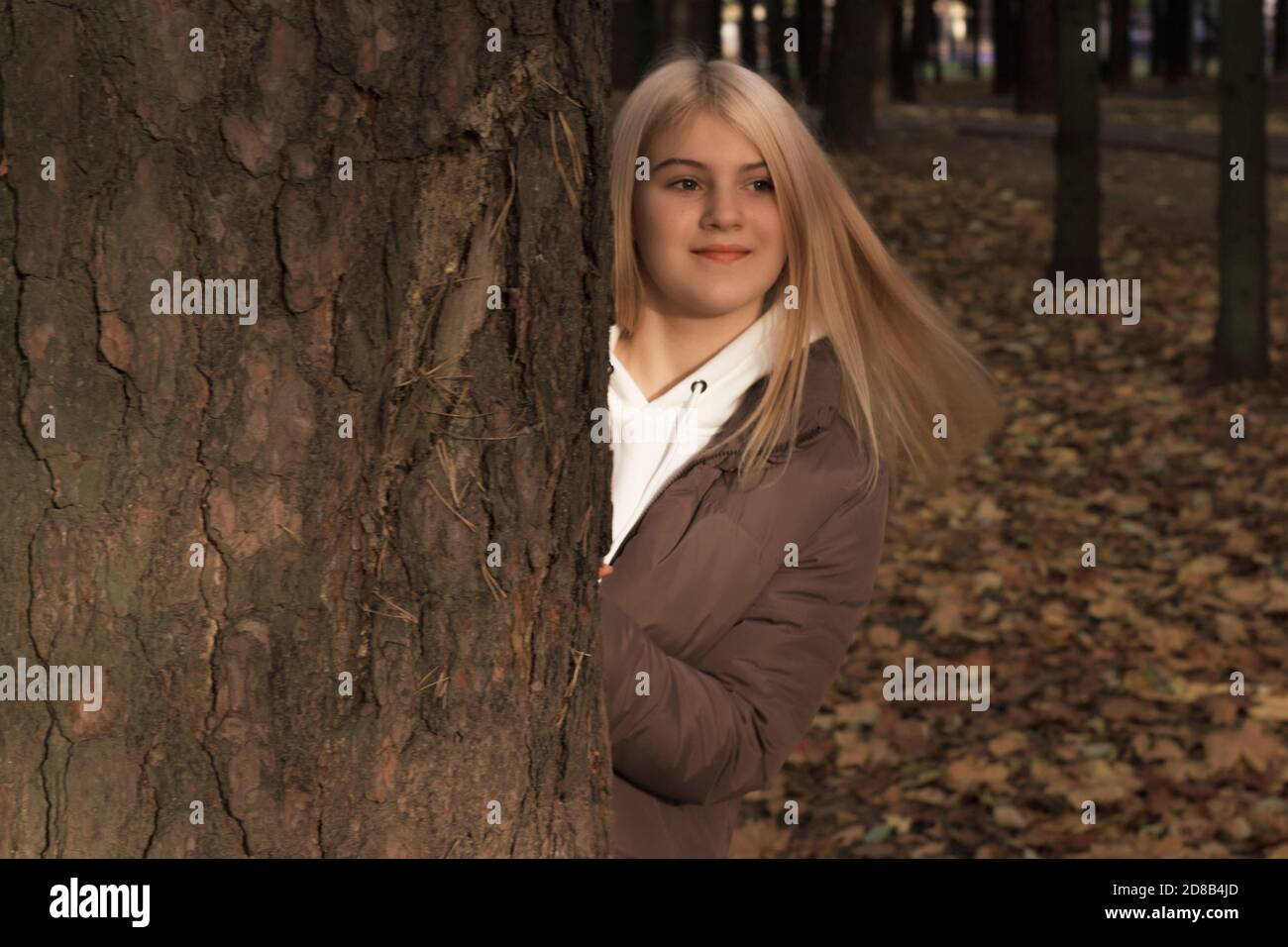 Ein junges Mädchen mit langen blonden Haaren auf einem Spaziergang in einem Herbstpark. Warme Farbe. Stockfoto