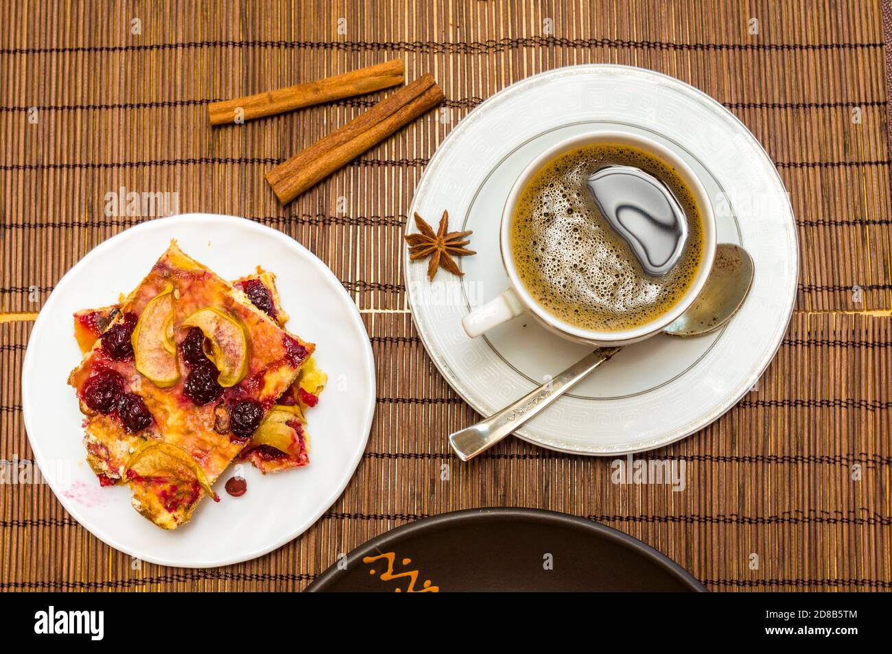 Stillleben - eine heiße Tasse schwarzen Kaffee, hausgemachte Kekse mit Obst, gebackene Äpfel auf einer Bambusmatte Stockfoto