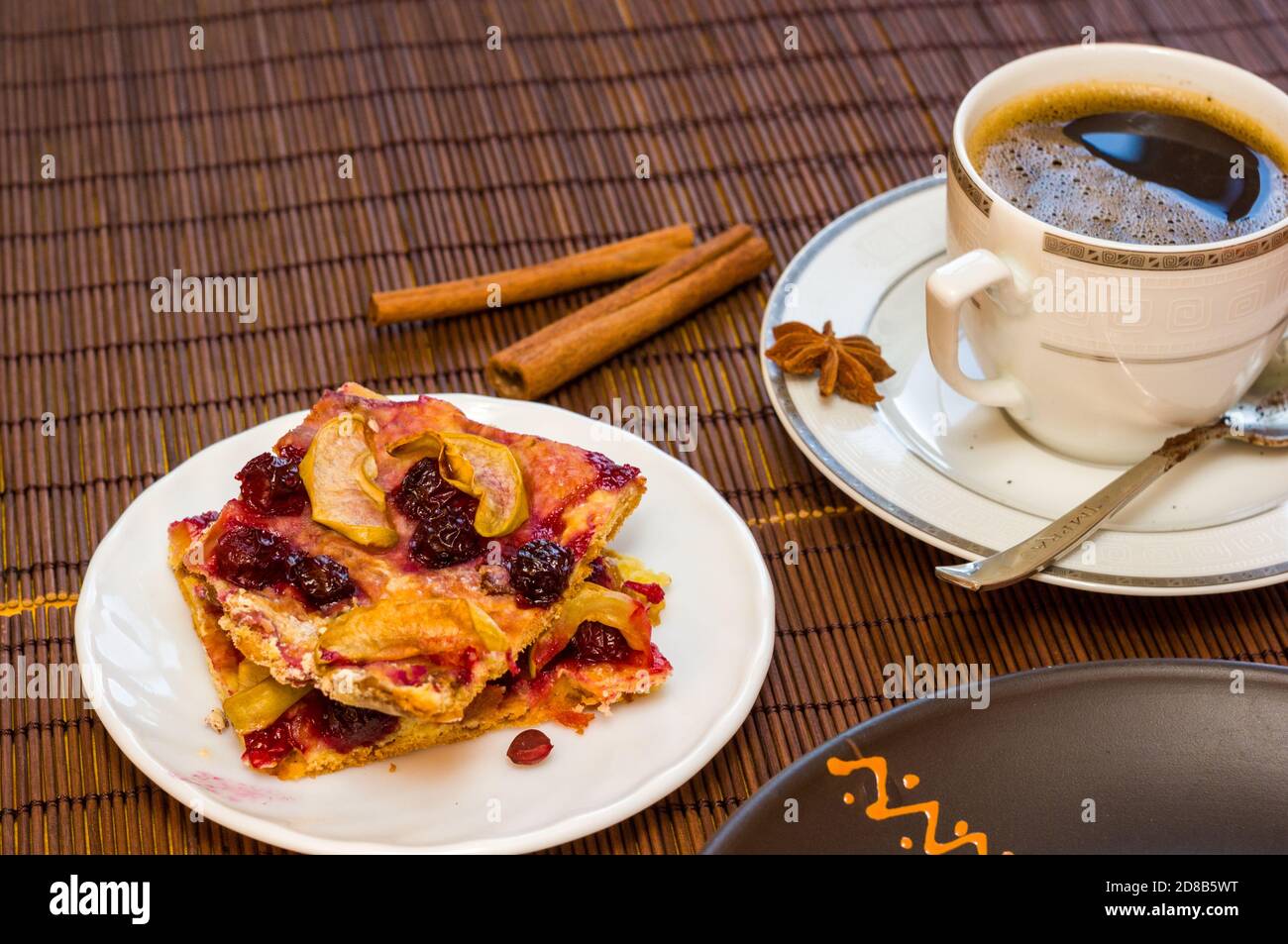 Stillleben - eine heiße Tasse schwarzen Kaffee, hausgemachte Kekse mit Obst auf einer Bambusmatte Stockfoto