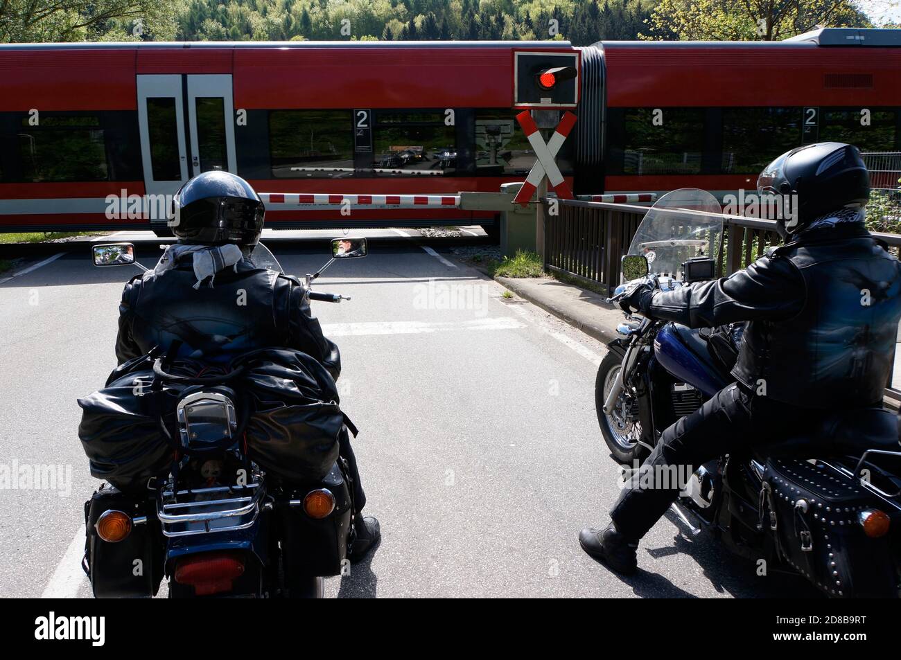 Zwei Motorräder warten vor einer geschlossenen Bahnschranke Stockfoto