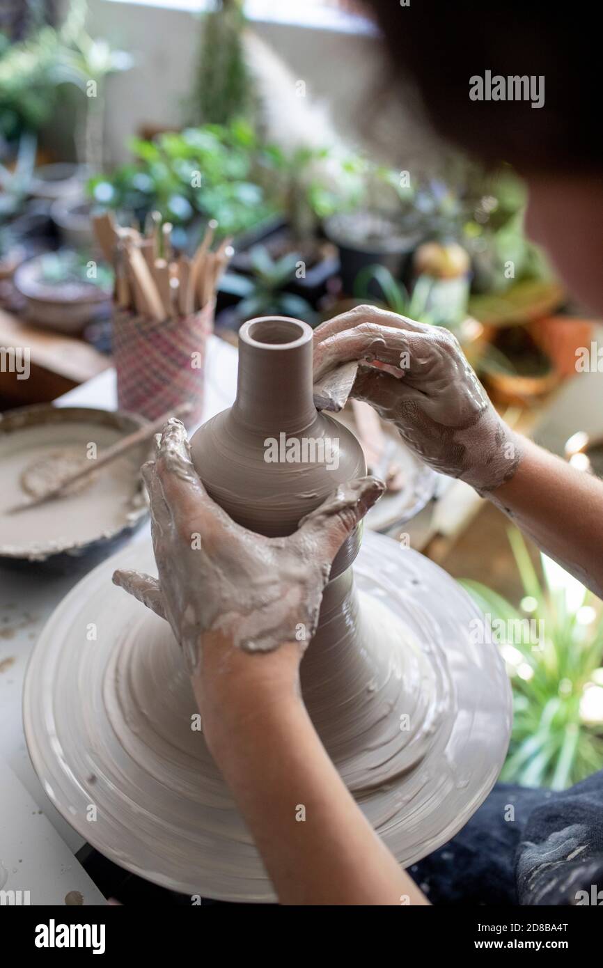 Nahaufnahme der Hände, die auf einem Keramiktopf arbeiten, mit Hintergrundbeleuchtung Stockfoto