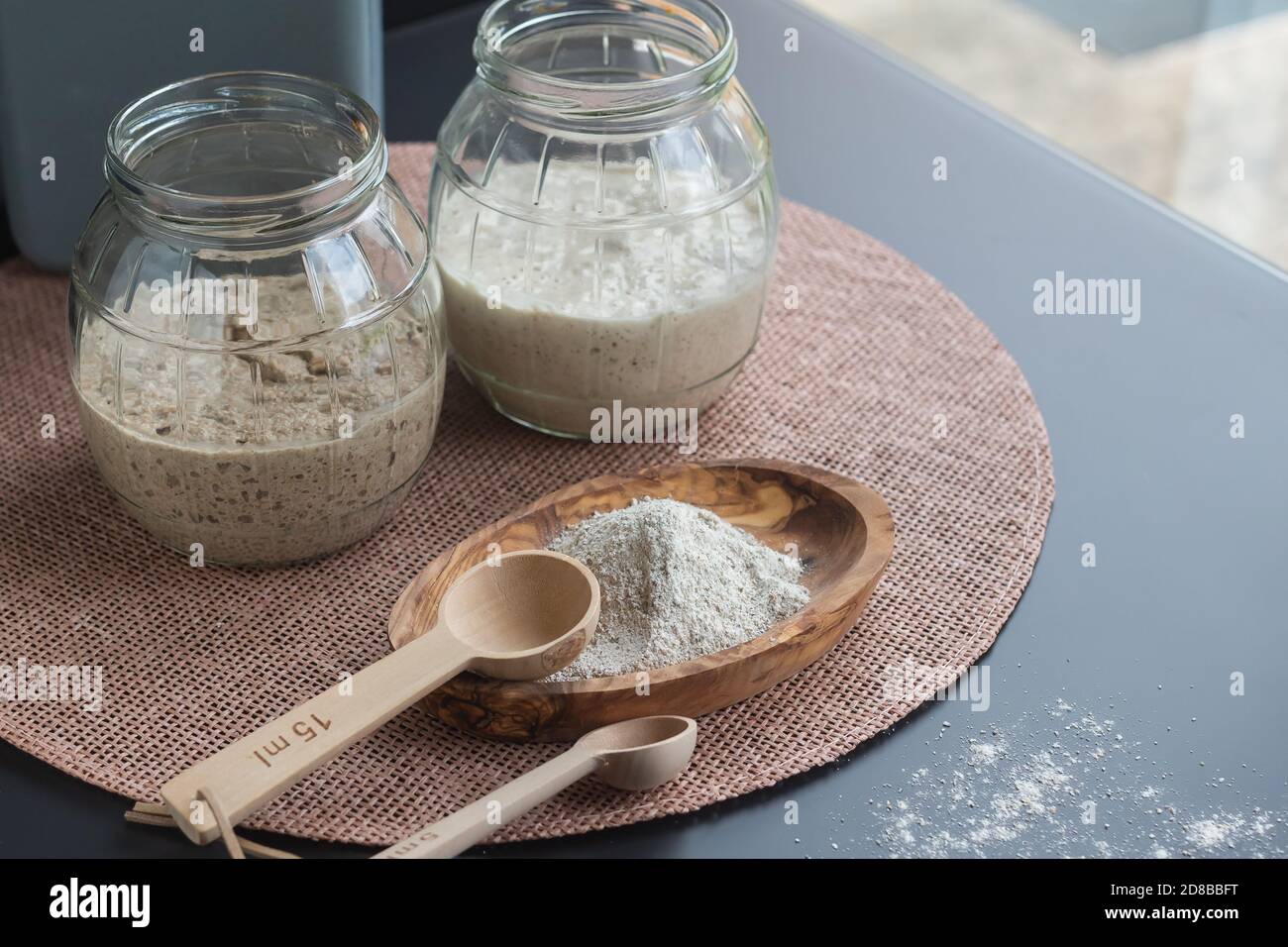 Natürliche Bio-Sauerteig-Vorspeisen: Frisch fermentierte Roggen- und Weizenvorspeisen in Gläsern, die zur Herstellung von Sauerteig-Brot verwendet werden können Stockfoto