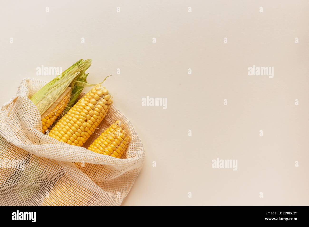 Herbst Erntehintergrund mit Kopierraum: Bio-Mais in wiederverwendbaren Baumwollnetztüten auf gelbem Hintergrund mit Kopierraum Stockfoto