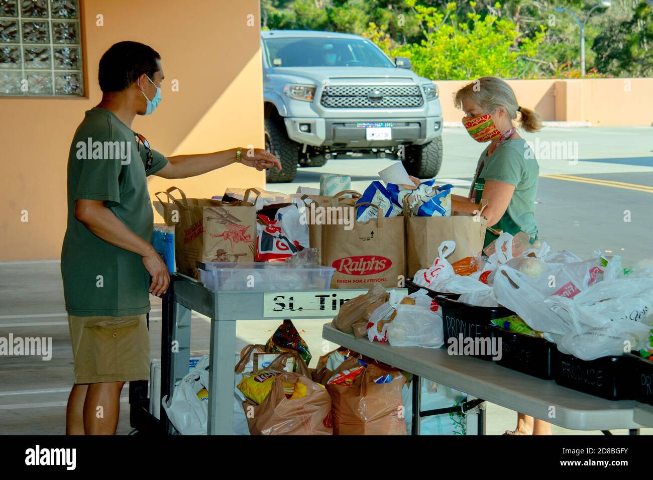 Freiwillige in der Speisekammer einer katholischen Kirche in Südkalifornien verteilen Lebensmittel, um durch Wohltätigkeitsempfänger zu fahren. Beachten Sie Gesichtsmasken aufgrund von Stockfoto
