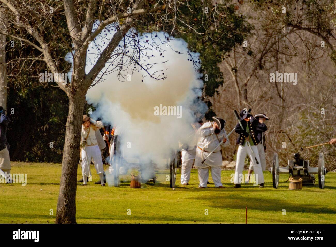 Britische Artillerie feuert, während Schütze ihre Ohren in einer historischen Nachstellung einer amerikanischen Schlacht des Revolutionären Krieges in einem Huntington Beach, CA, par Stockfoto