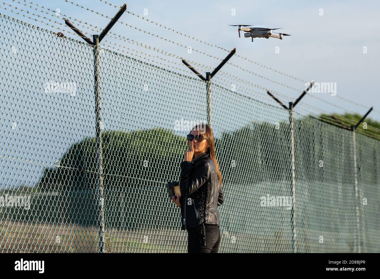 Frau, die Drohne in der verbotenen Zone fliegt. Fliegen Sie ohne Lizenz. Flugdrohne in der Nähe des Flughafens. Drohne Gesetzgebung.Drohne als Spionagewerkzeug Stockfoto