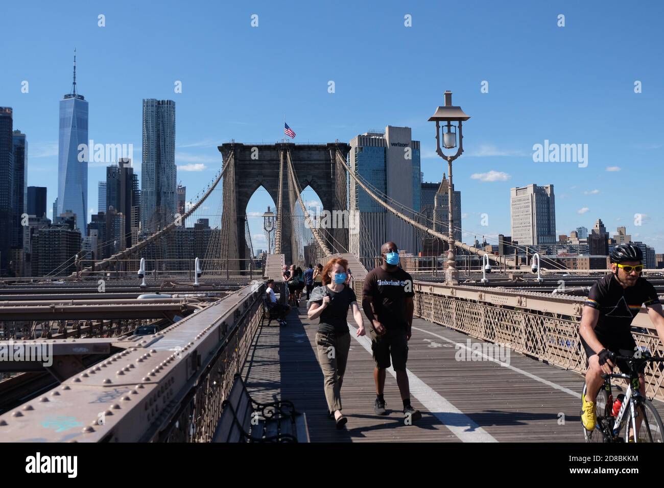 Maskierte Touristen gehen im Sommer 2020 über die Brooklyn Bridge Stockfoto