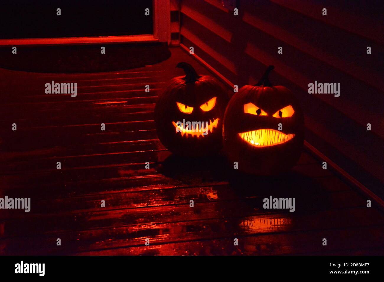Geschnitzte Kürbisse leuchten an Halloween auf der Veranda eines Hauses. Stockfoto