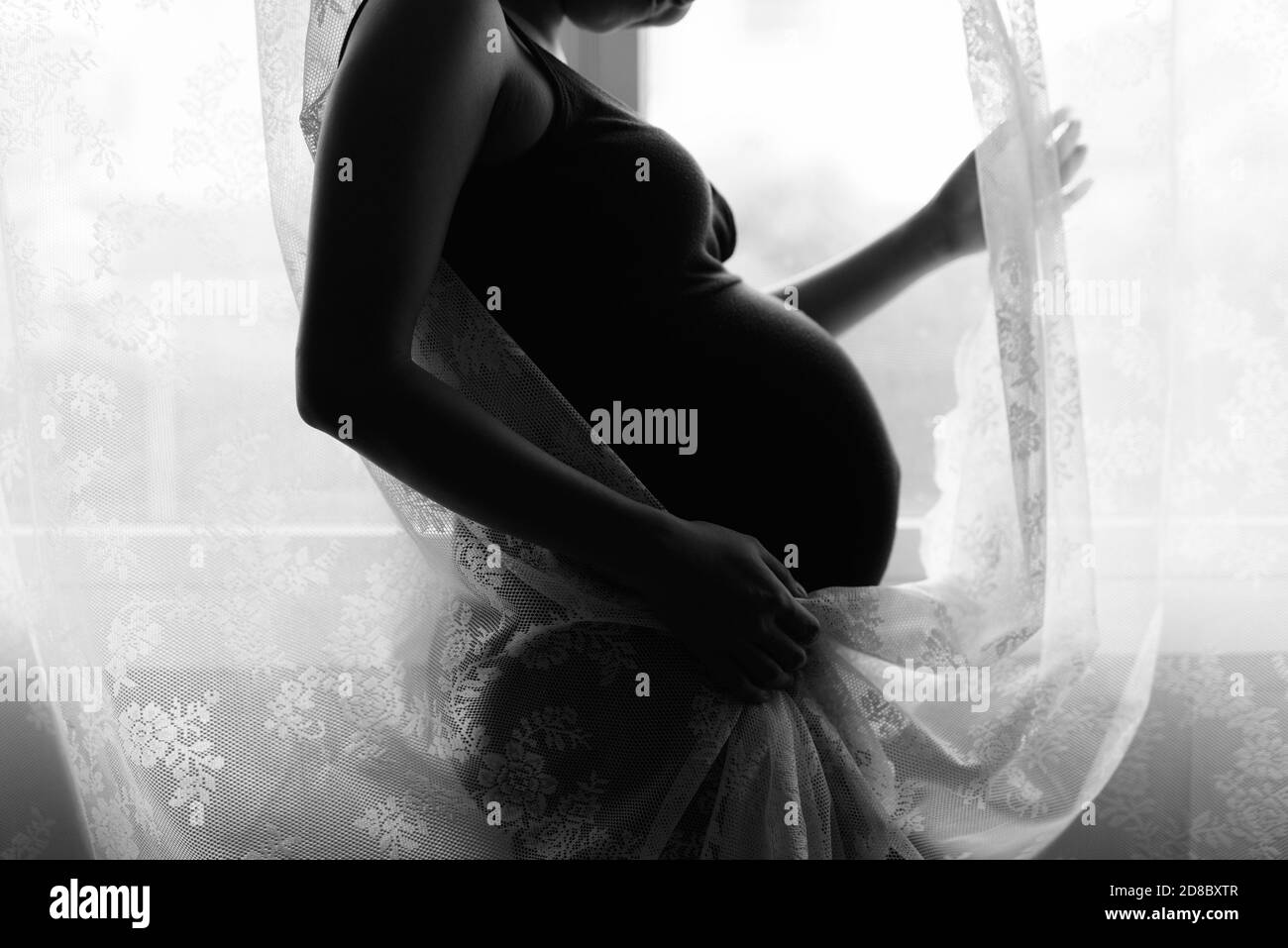 Liebevolle Mutter ihr Baby in Silhouette durch das Fenster Stockfoto