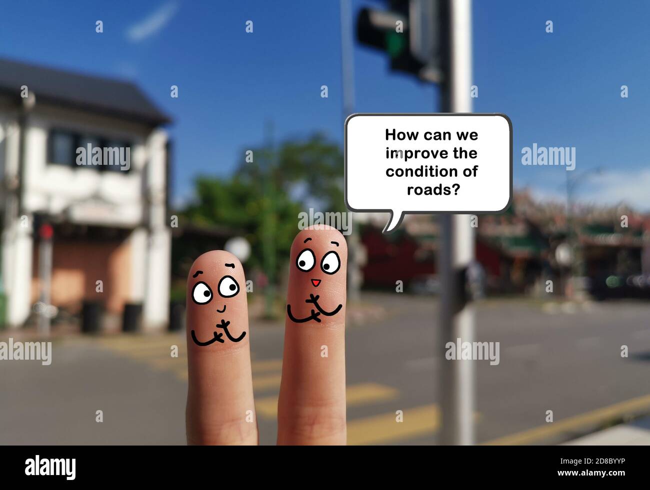 Zwei Finger sind als zwei Personen dekoriert. Sie diskutieren über Möglichkeiten, den Straßenzustand zu verbessern. Stockfoto