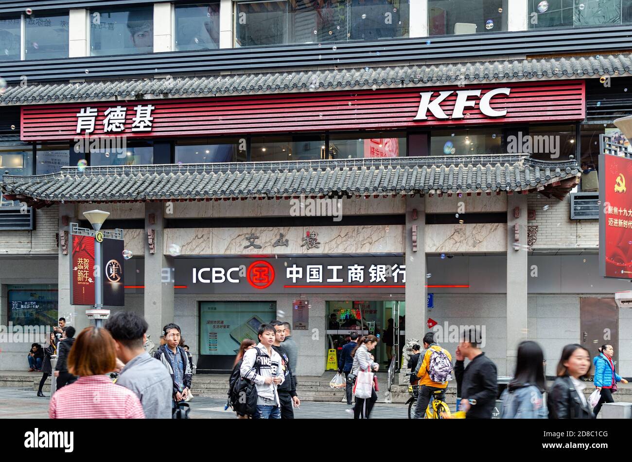 Außenansicht des Restaurants KFC und ICBC Bankfiliale in der chinesischen Straße. Straße mit Menschen, die sich drängen. Shenzhen, China, 2018-03-08. Foto mit Unschärfen in m Stockfoto