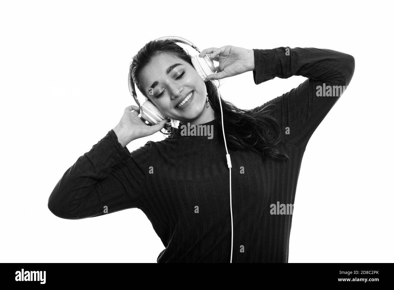 Junge indische Frau glücklich lächelnd, während Sie Musik hören mit geschlossenen Augen Stockfoto