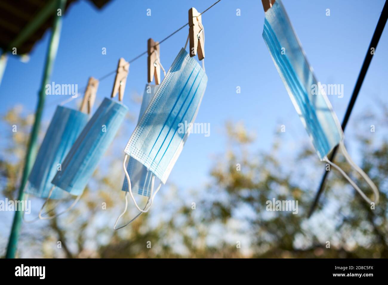 Sonnenbeschienene Gesichtsmasken werden zum Trocknen aufgehängt, um sie mit Holzkäfelchen zu desinfizieren. Neues normales Konzept Stockfoto